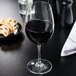 A Carlisle red wine glass filled with red wine sits on a table next to cookies.