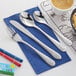Acopa 18/0 stainless steel children's flatware on a blue napkin with a spoon and fork.