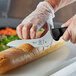 A person using a Mercer Culinary bread knife to cut a loaf of bread.