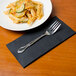 A plate of pasta and a fork on a black Hoffmaster FashnPoint dinner napkin.