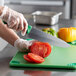A person using a Dexter-Russell chef knife to cut tomatoes on a cutting board.