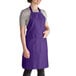 A woman wearing a purple Intedge bib apron with pockets.