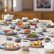 Luzerne white porcelain coupe plates with gray speckles on a table with plates of food.