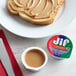 A piece of toast with Jif Creamy Peanut Butter on a plate with a jar of Jif Creamy Peanut Butter.