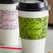 Two white coffee cup sleeves with a customizable embossed surface with the words "your logo here" in green.