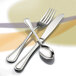 Oneida Barcelona stainless steel serving spoon on a table with a fork and spoon.
