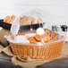 A clear round food display cover on a table with baskets of pastries.