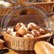A clear round polyweave cover on a basket of bread rolls.