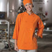 A woman wearing an orange Uncommon Chef coat with customizable sleeves.