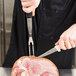 A person cutting meat with a Dexter-Russell V-Lo pot fork and knife.
