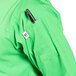 A person wearing a lime green Uncommon Chef 3/4 sleeve chef coat with a black object in the pocket.