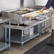 A man cooking food on a Regency stainless steel equipment stand in a commercial kitchen.