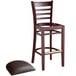 A Lancaster Table & Seating mahogany wood ladder back bar stool with dark brown vinyl seat sitting on a table.