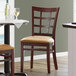 A Lancaster Table & Seating wood restaurant chair with light brown vinyl seat.