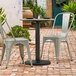 A Lancaster Table & Seating Excalibur outdoor table base plate on a table with chairs on a brick patio.