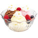 A close-up of a Cambro clear polycarbonate swirl bowl filled with ice cream, berries, and whipped cream.