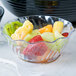 A bowl of fruit in a Cambro clear swirl bowl on a table.