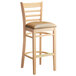 A Lancaster Table & Seating wooden bar stool with a light brown cushion.