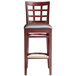 A Lancaster Table & Seating mahogany wood bar stool with a dark brown cushioned seat and window back.