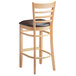 A Lancaster Table & Seating wooden ladder back bar stool with a dark brown vinyl seat.