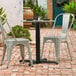 A table and chairs on a brick patio with a Lancaster Table & Seating Excalibur outdoor table base.