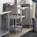 A man using a Regency stainless steel equipment stand in a kitchen.