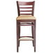 A Lancaster Table & Seating mahogany wood bar stool with light brown vinyl seat.