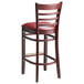 A Lancaster Table & Seating mahogany wood bar stool with a detached burgundy vinyl seat.
