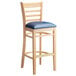 A Lancaster Table & Seating wood ladder back bar stool with a navy vinyl seat.