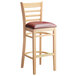 A Lancaster Table & Seating wooden bar stool with a burgundy cushion.