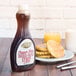 A Golden Barrel Sugar Free Pancake and Waffle Syrup bottle on a table next to a plate of waffles and a glass of milk.