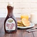 A Golden Barrel Sugar Free Pancake and Waffle Syrup bottle next to a plate of waffles and a glass of milk.