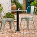 A Lancaster Table & Seating Excalibur outdoor table base column on a table with two chairs on a brick patio.
