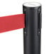 A black Aarco crowd control stanchion with a red retractable belt.
