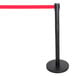 A black Aarco crowd control stanchion with a red retractable belt.