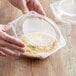 A person holding a clear plastic container with pie inside.