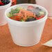 A close-up of a salad in a Dart foam container.