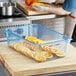 An Araven blue plastic food pan filled with sliced oranges on a cutting board in a kitchen.