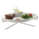 A Cal-Mil white plate stand holding a plate of steak and vegetables on a white surface.