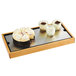 A Cal-Mil Madera rustic pine tray with a cake and three glasses of yogurt on it.