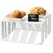 A Cal-Mil white metal square riser holding a tray of cookies and muffins.