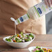 A person pouring Hellmann's Caesar dressing into a bowl of salad.