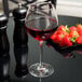 A Chef & Sommelier Cabernet wine glass filled with red wine next to strawberries.