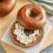 A close up of a New York style Pumpernickel bagel with cream cheese on top.