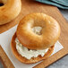A close up of an Original Bagel New York Style Apple Cinnamon Bagel with cream cheese on top.