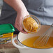 A person using a whisk to stir a bowl of liquid with Knorr Ultimate Chicken Bouillon Base.