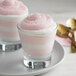 Two glasses of pink and white Knorr neutral mousse on a plate with gold spoons.