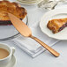 A piece of pie on a plate with an American Metalcraft hammered bronze pie server.