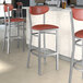 A group of Lancaster Table & Seating Boomerang Series bar stools with burgundy seats at a counter.