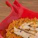 A red CAC Festiware fry pan plate with rice and chicken served on it.